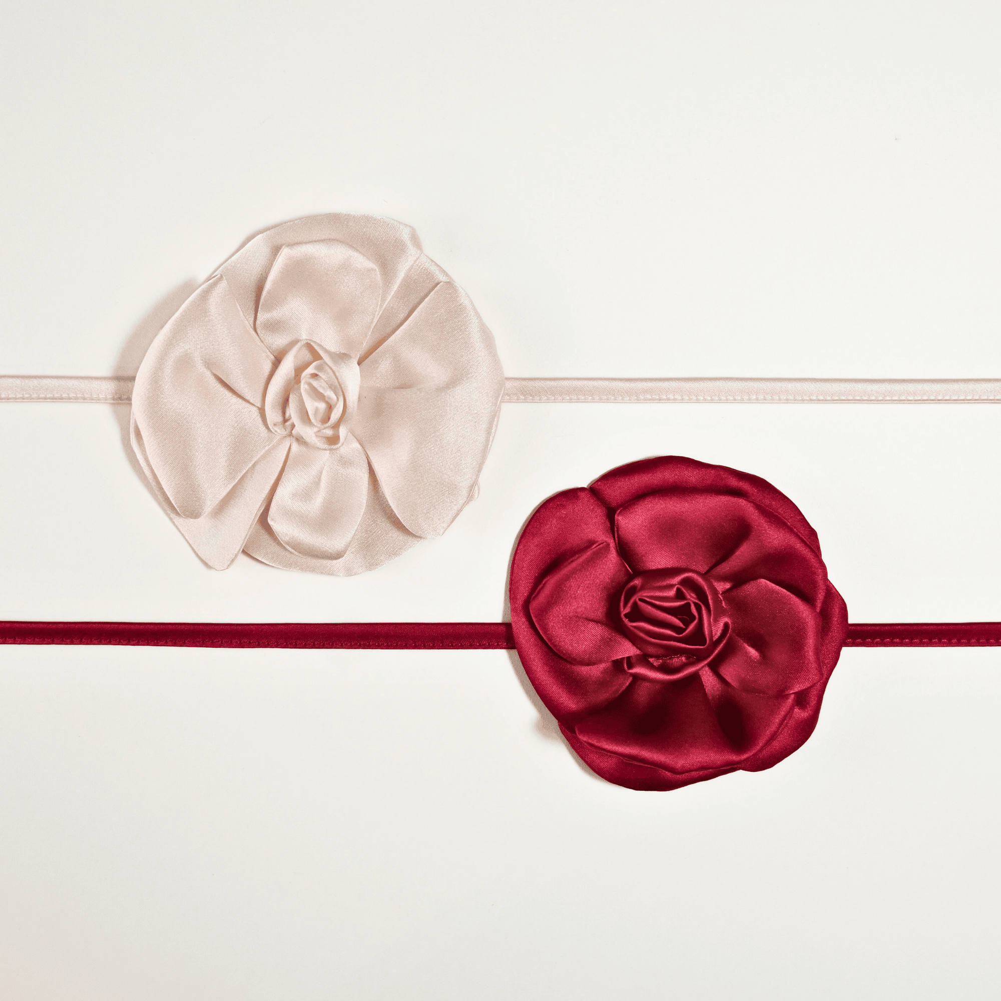 Collane choker Alkira Collection in raso di pura seta con fiore cucito a mano, nelle varianti colore bianco e burgundy, fotografate su sfondo bianco in vista dall’alto.