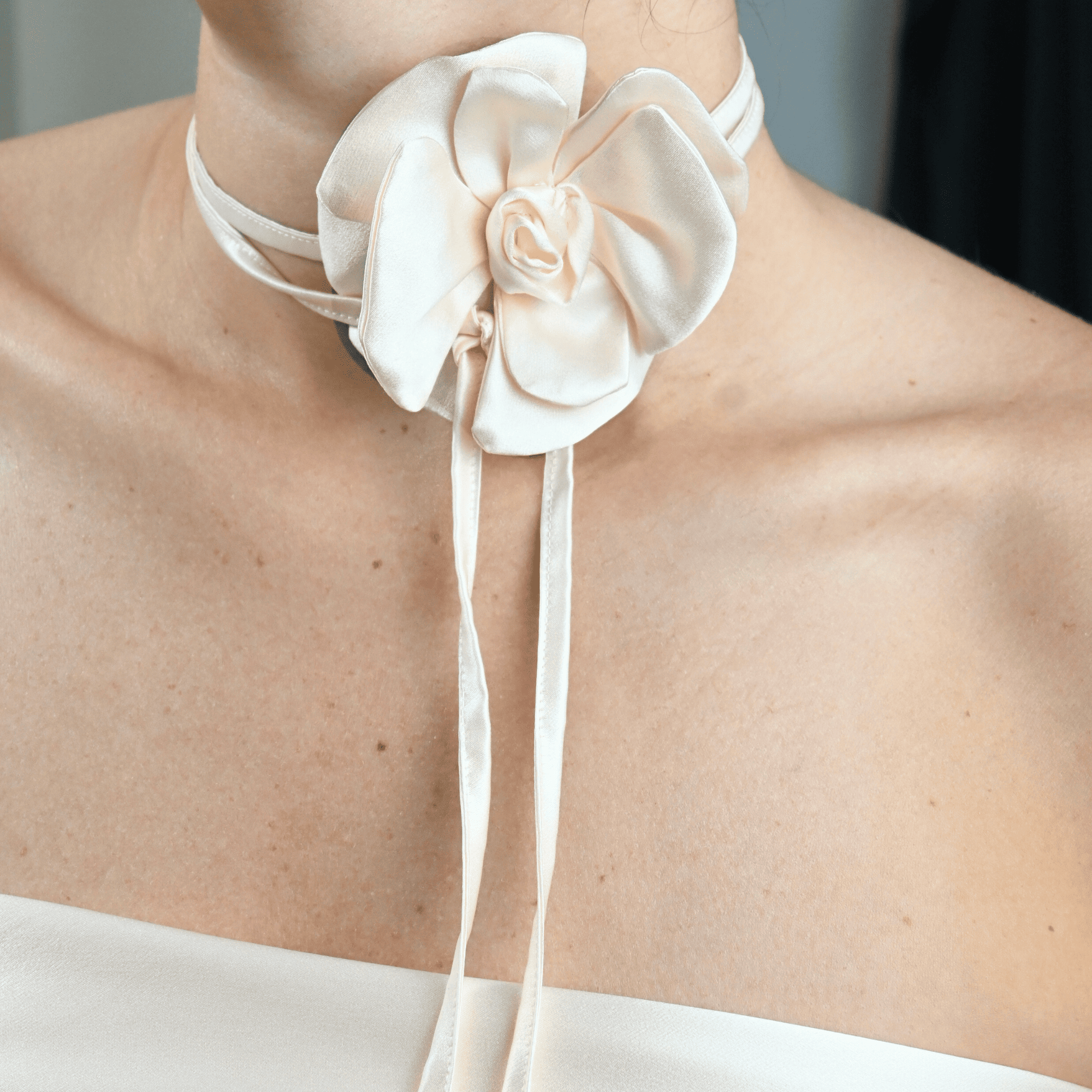 Collana choker da donna in raso di pura seta con fiore artigianale color bianco panna, cucito a mano petalo per petalo, indossata al collo su sfondo neutro, stile elegante firmato Alkira Collection, ideale per occasioni serali.