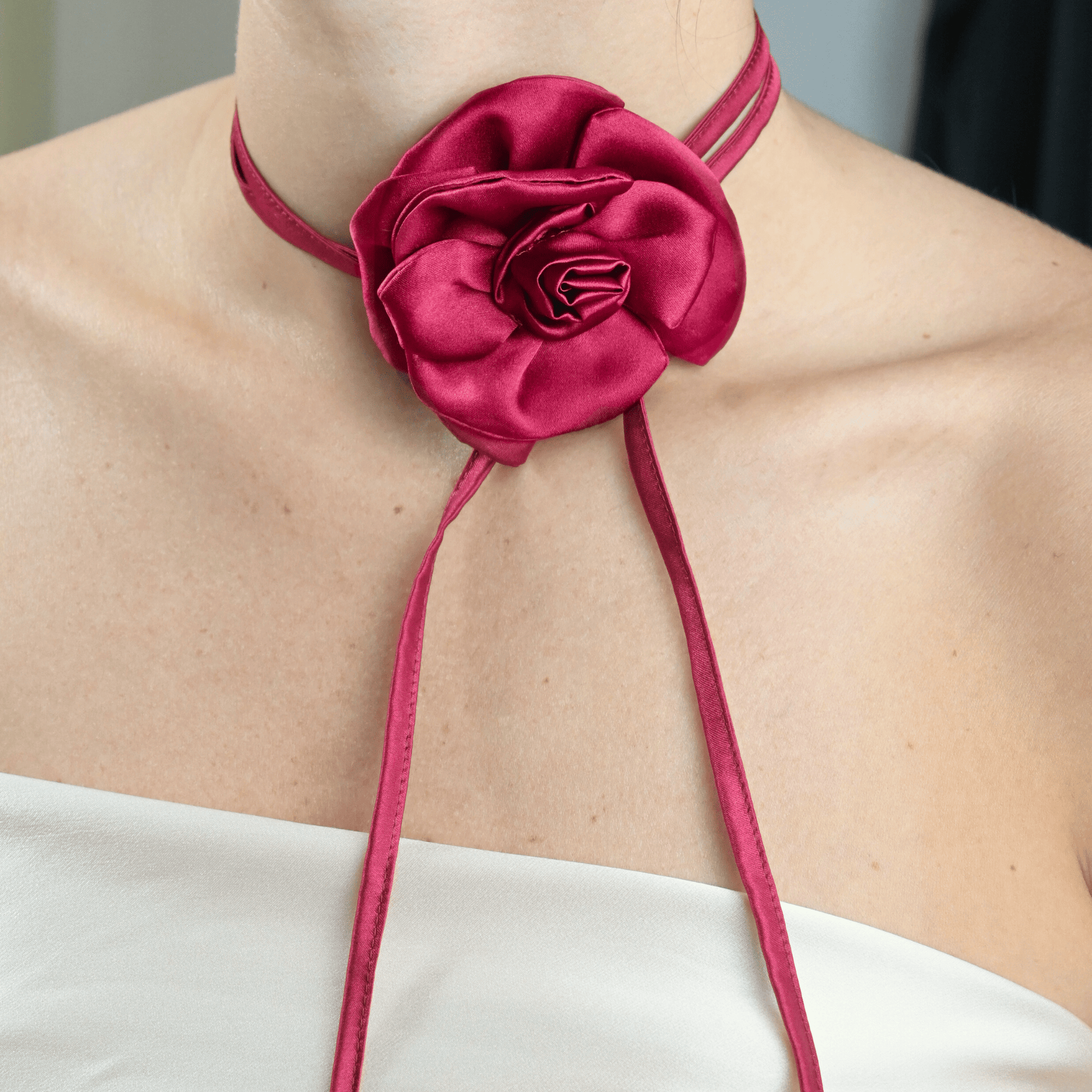 Collana choker da donna in raso di pura seta con fiore artigianale color burgundy, cucito a mano petalo per petalo, indossata al collo su sfondo neutro, stile elegante firmato Alkira Collection, ideale per occasioni serali.
