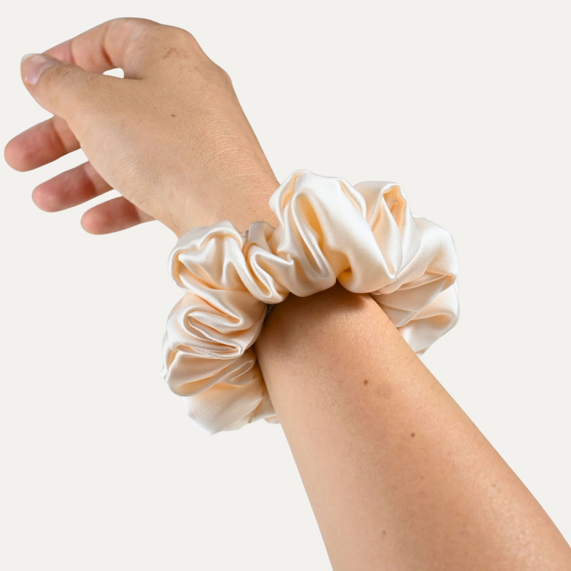 Scrunchie in seta pura con fodera in cotone, color bianco perla, stile elegante, indossato da modella dove si puó capire la grandezza dell'oggetto