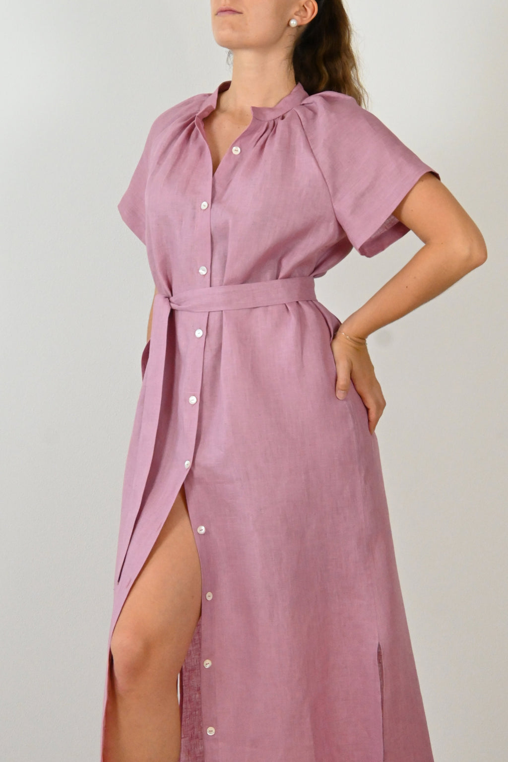 Modella in un vestito di lino rossa da donna, con spacco laterale e cintura. Ideale per un look estivo e versatile, riflette la qualità del lino Made in Italy.