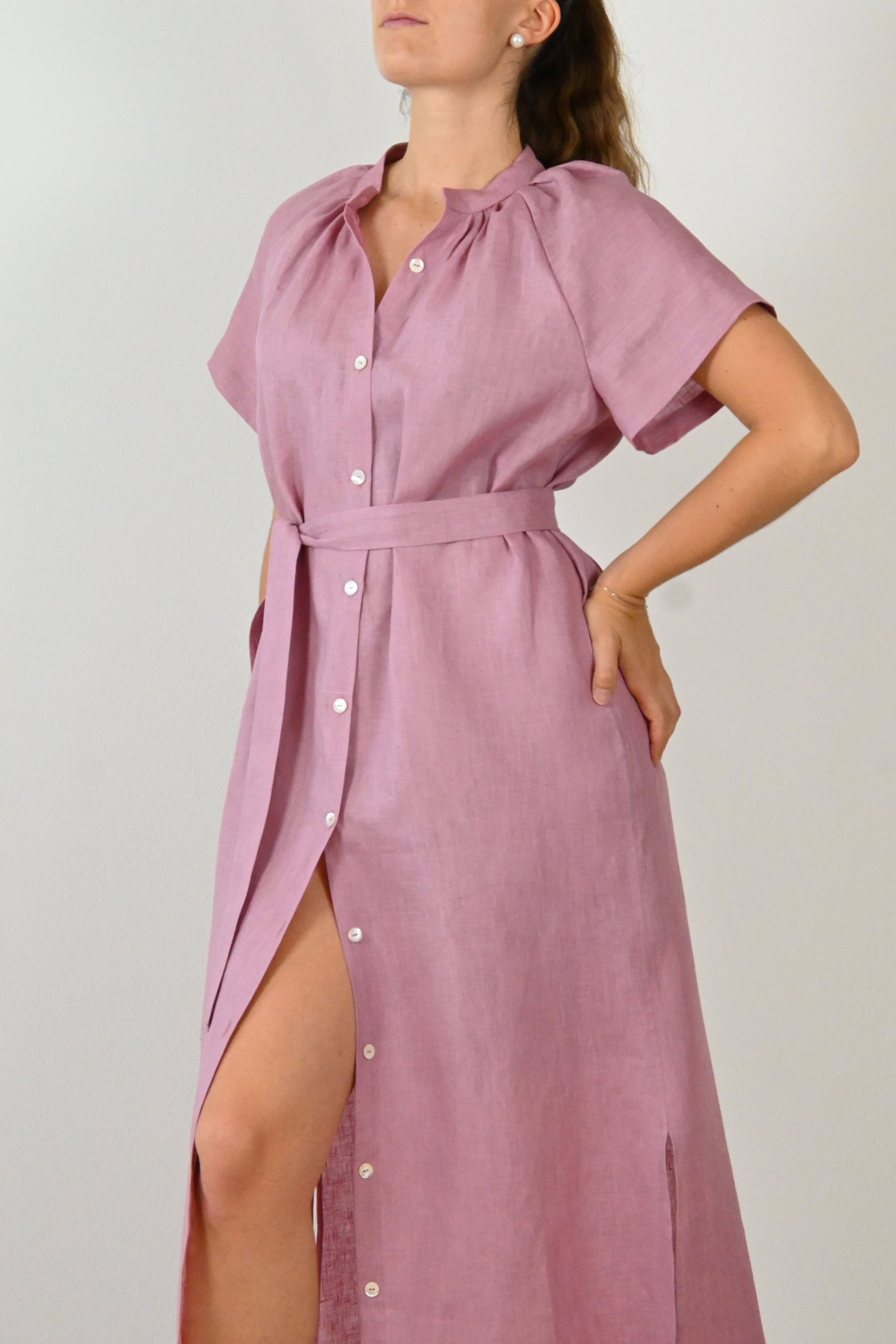 Modella in un vestito di lino rossa da donna, con spacco laterale e cintura. Ideale per un look estivo e versatile, riflette la qualità del lino Made in Italy.